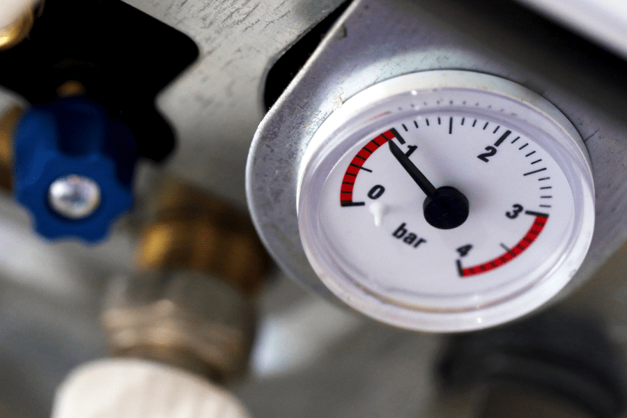 A pressure gauge on the front of a boiler measuring less than one bar, indicating it has low pressure.