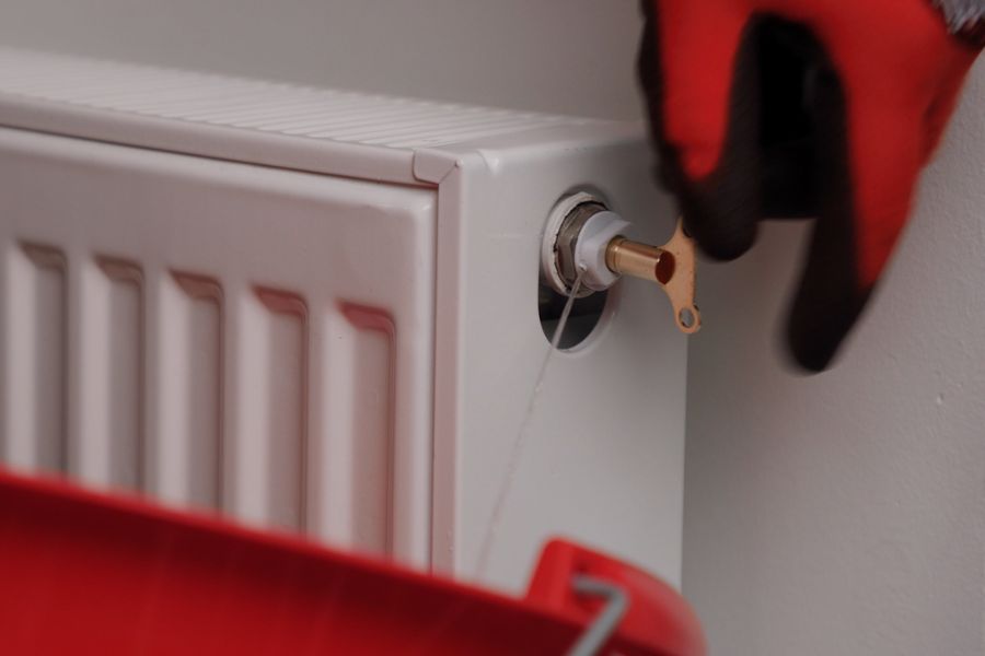 Bleeding a radiator until water comes out of the valve to reduce boiler pressure