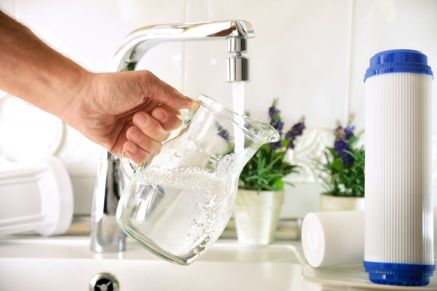 An individual holds a jug under their tap as it pours out water to test their water pressure.