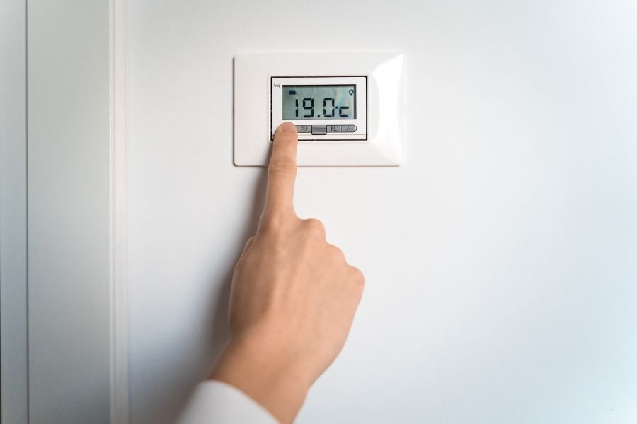 Person turning their thermostat down or off before going to bed
